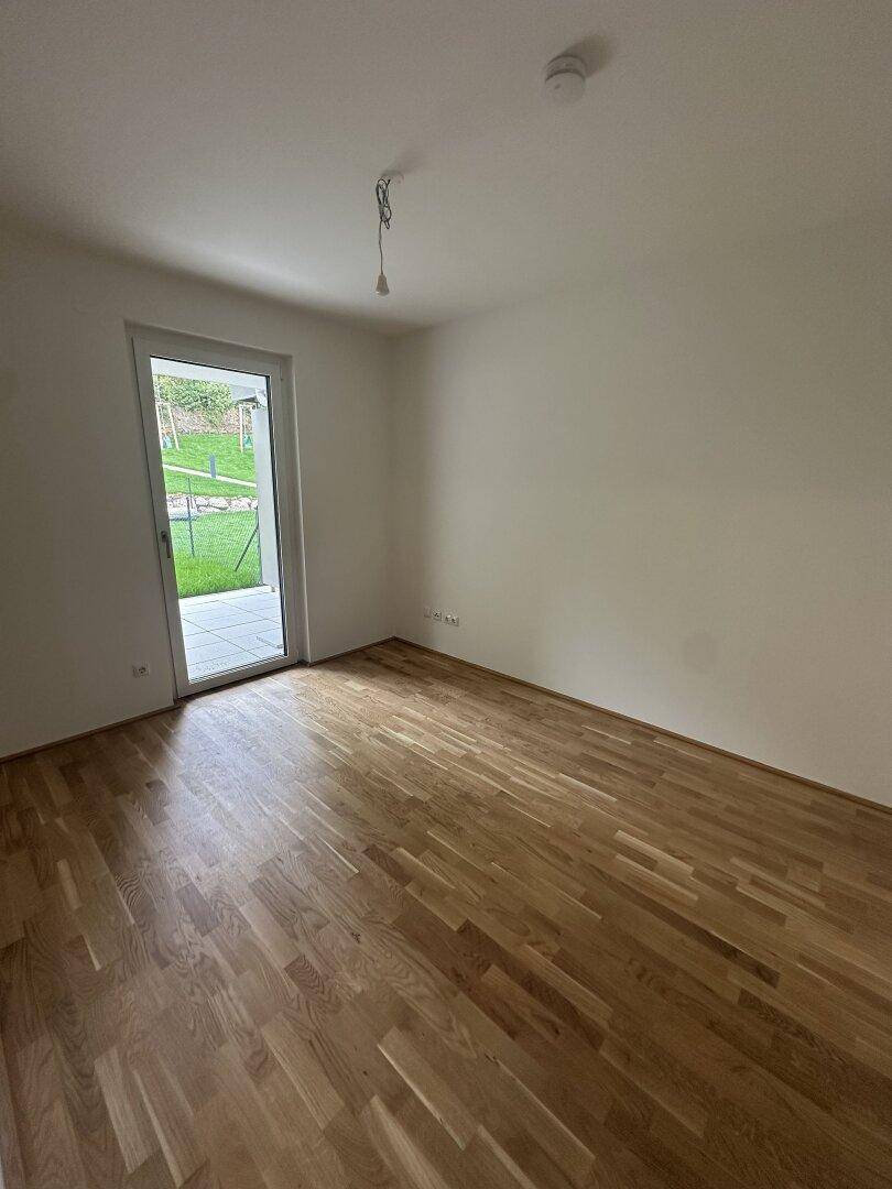 Heller Raum mit Eichenparkett und Zugang zu einer Terrasse oder einem Gartenbereich.