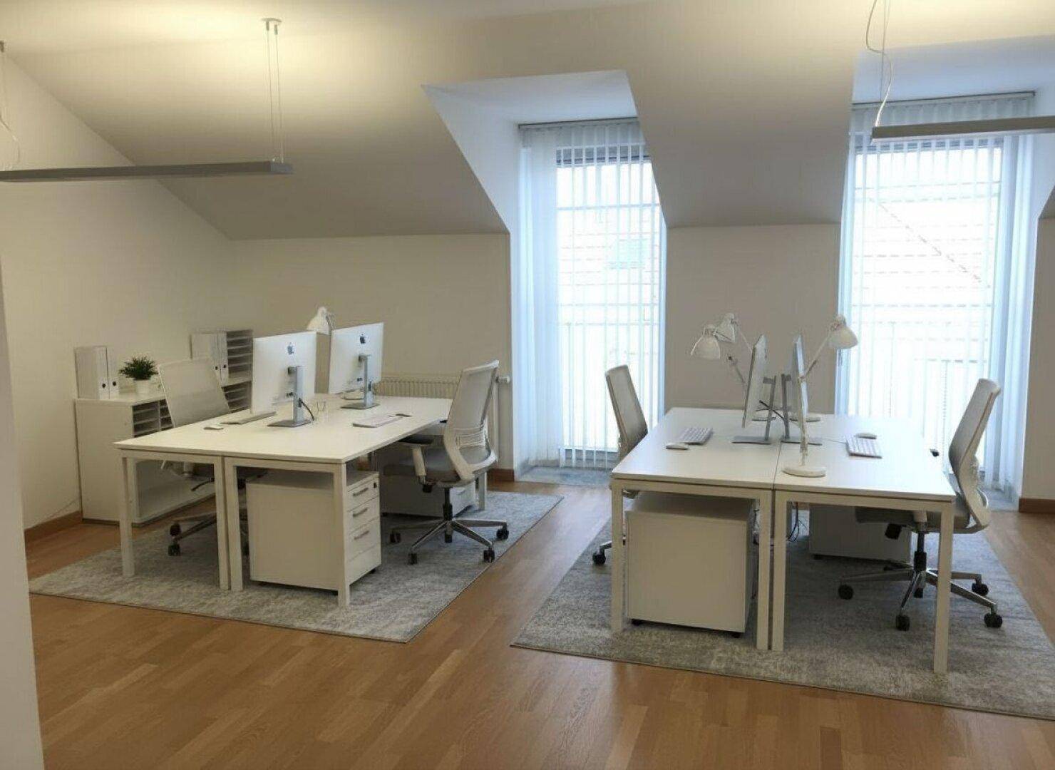 Offener Bürobereich im Dachgeschoss mit mehreren Arbeitsplätzen, Computern und viel Tageslicht.