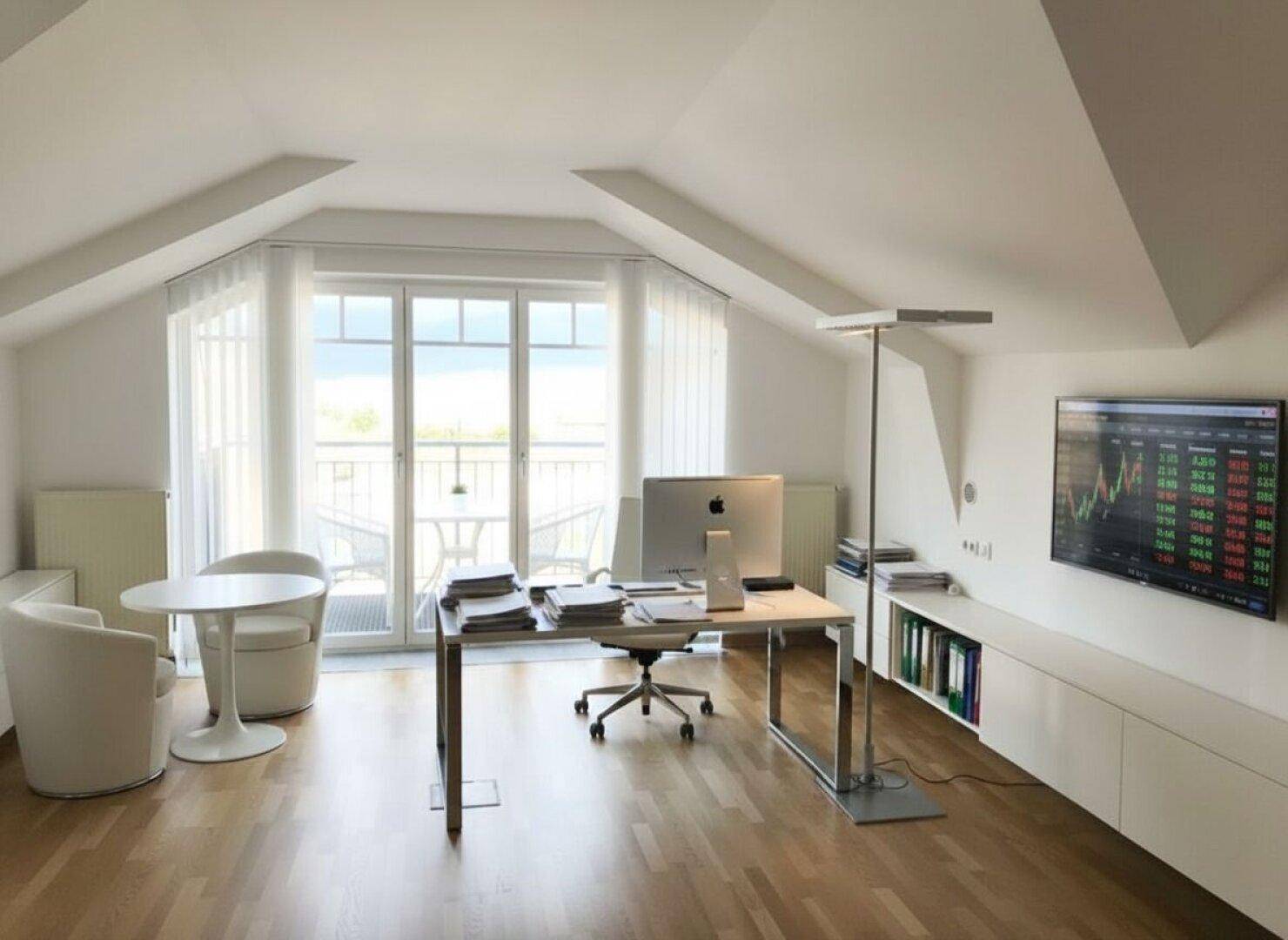 Helles Büro im Dachgeschoss mit modernem Arbeitsplatz, Fernseher und Zugang zu einem Balkon.