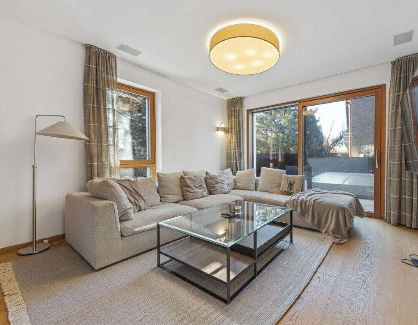 Gemütliches Wohnzimmer mit großem Sofa, modernem Couchtisch und direktem Zugang zur Terrasse durch breite Fenster.