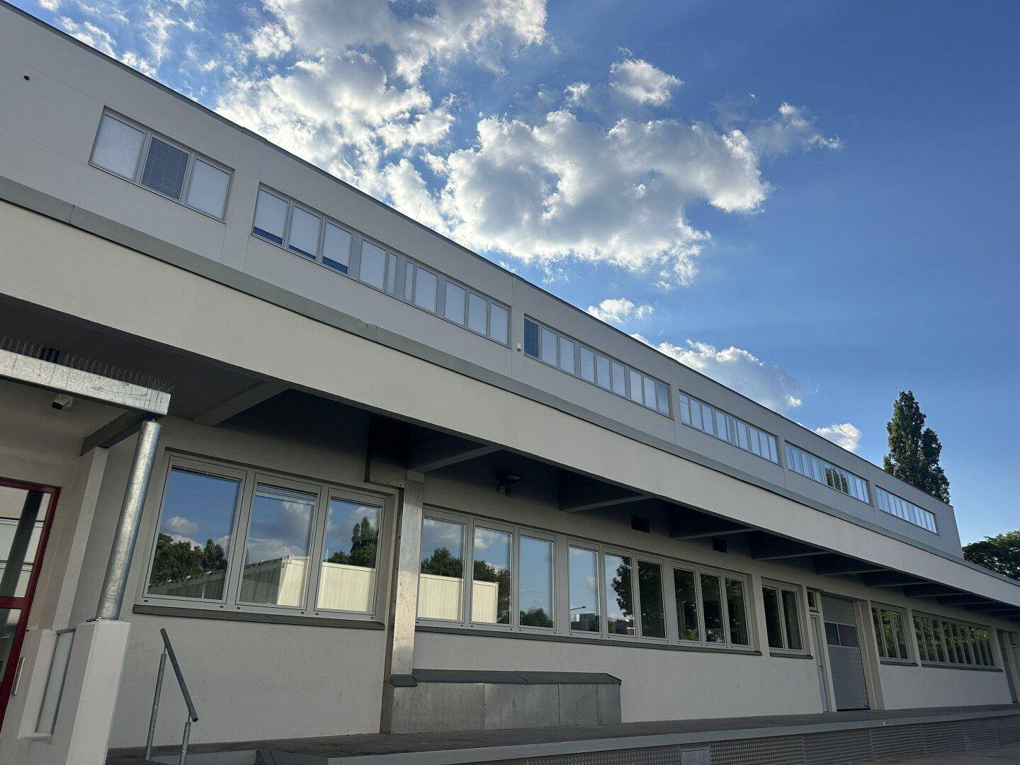 Moderne Gebäudefassade mit vielen Fenstern und klarem Himmel im Hintergrund.