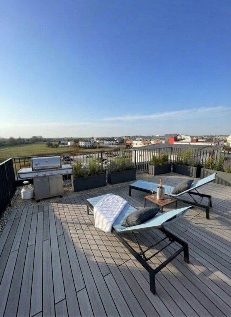Geräumige Dachterrasse mit Sonnenliegen, Grillbereich und weitem Blick ins Grüne.