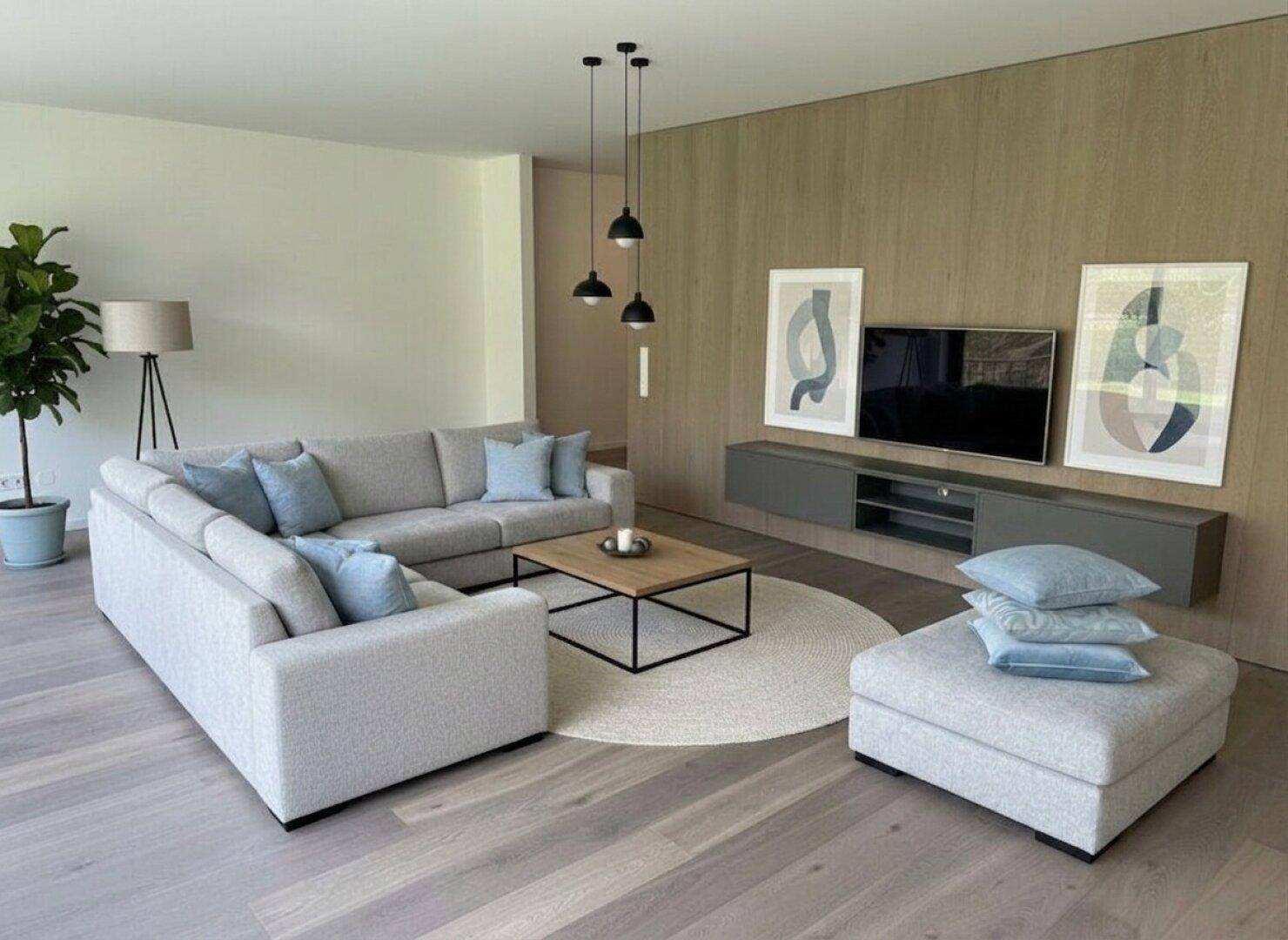 Helles Wohnzimmer mit großem Ecksofa, modernem Couchtisch und stilvoller Wandgestaltung.