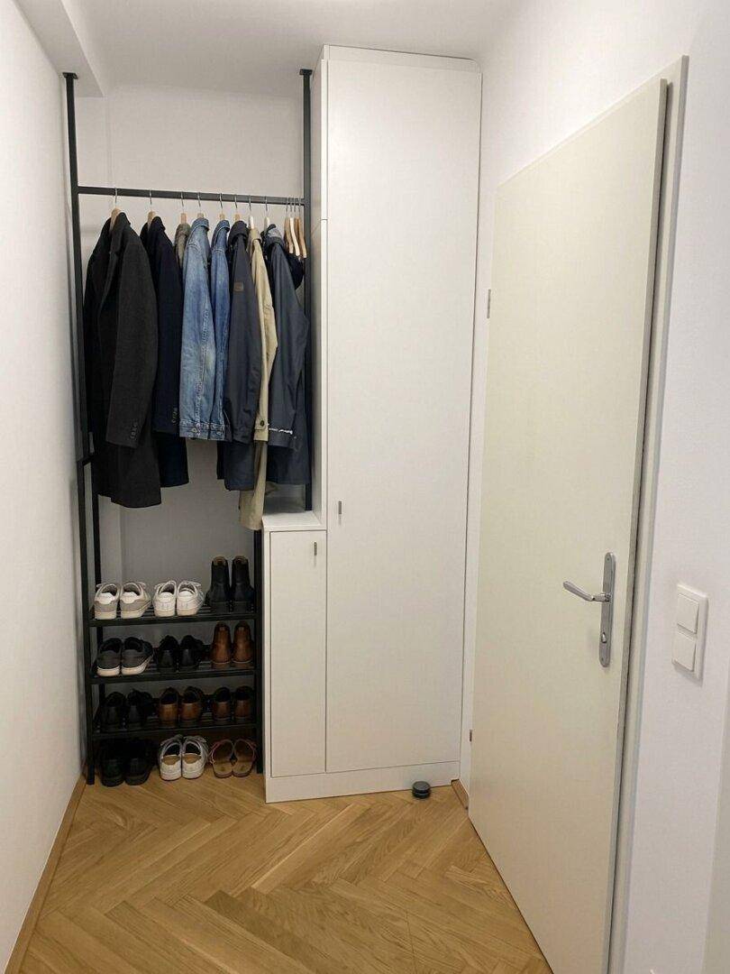 Heller Eingangsbereich mit praktischer Garderobe, Schuhregal und Fischgrätparkett.