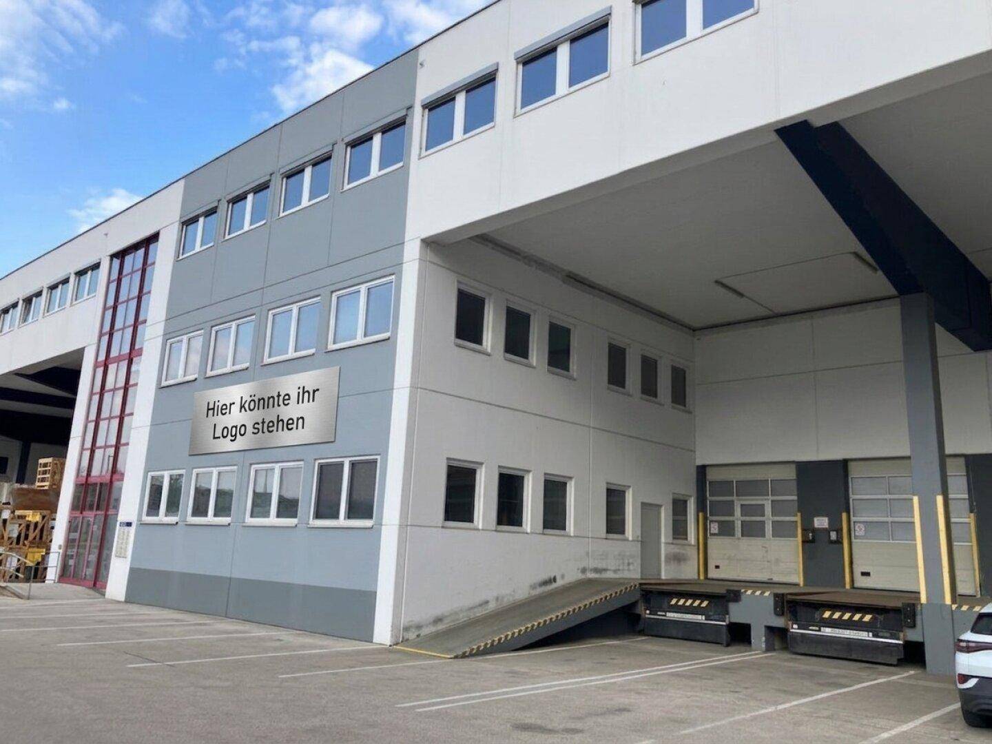 Gewerbegebäude mit grauer Fassade, Laderampen und einer Rampe für den Zugang.