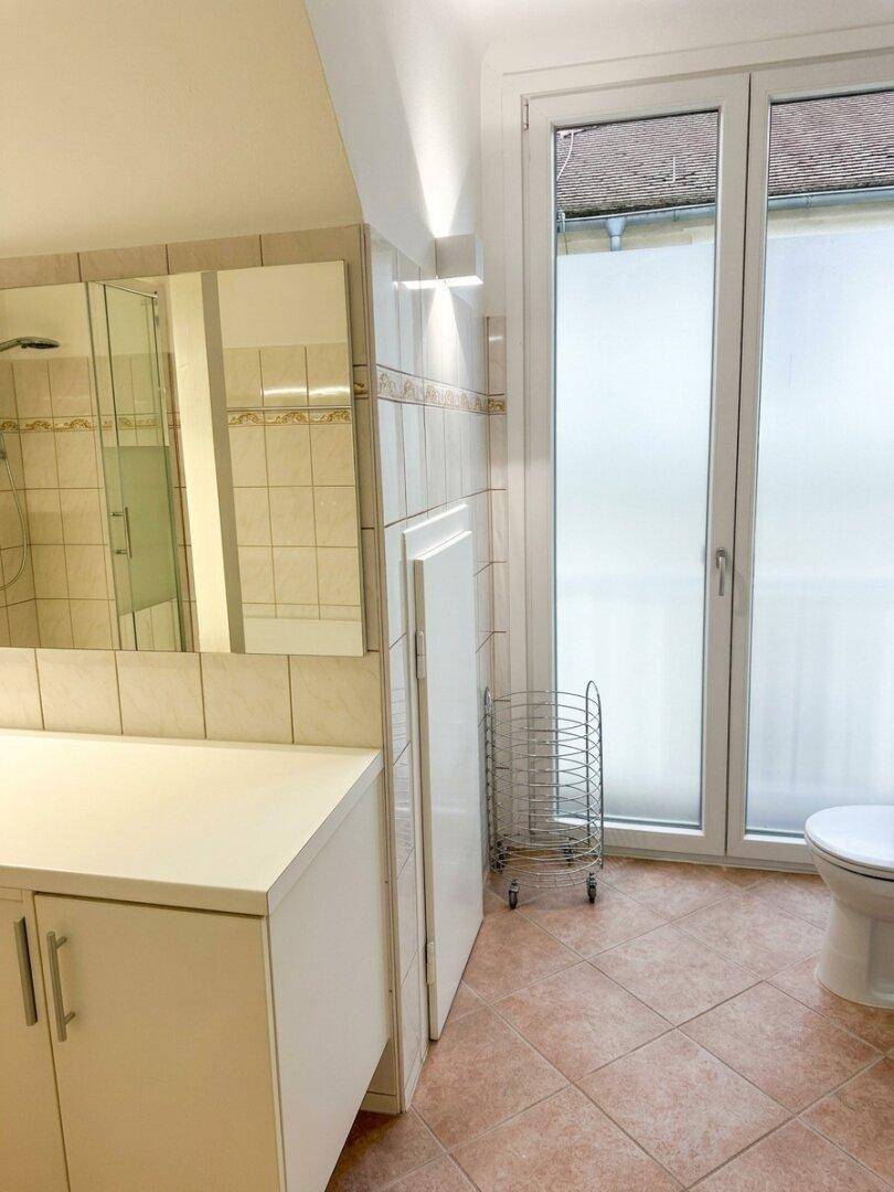 Badezimmer mit Waschtisch, Toilette und Fenster mit Milchglas für Privatsphäre.