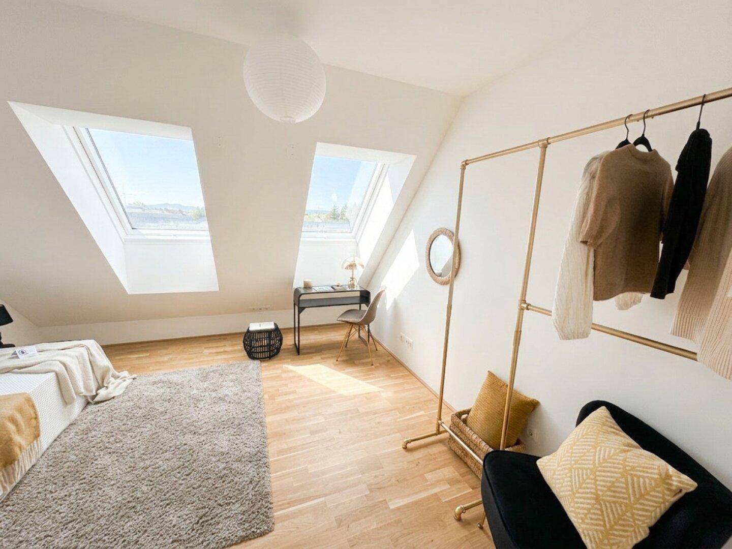 Gemütliches Schlafzimmer mit Dachschrägen und zwei großen Dachfenstern, die viel Licht hereinlassen.