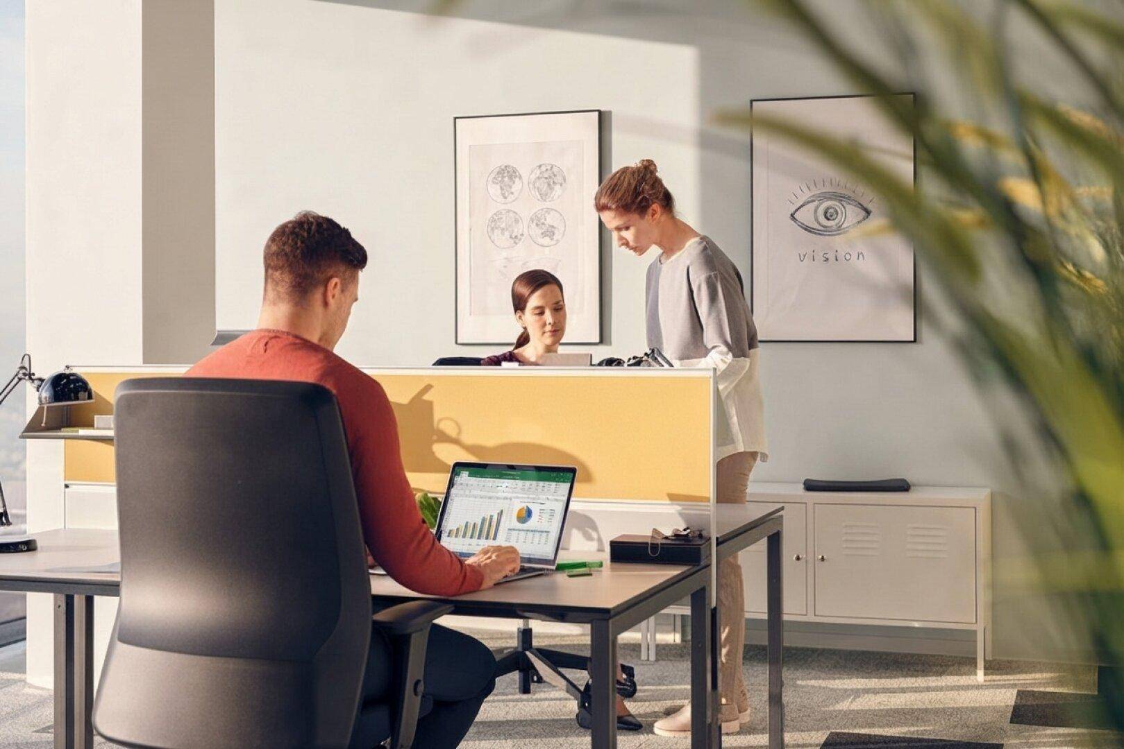 Moderner Arbeitsplatz in einem hellen Büro mit ergonomischem Stuhl, Laptop und dekorativen Wandbildern.