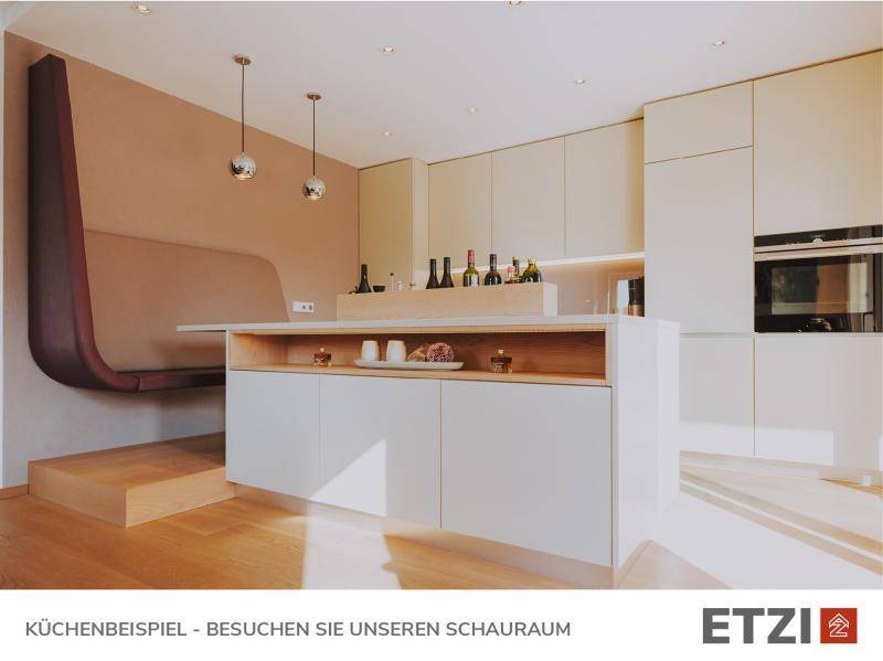 Moderne Küche mit heller Holzoptik, integriertem Essbereich und hochwertigen Geräten.