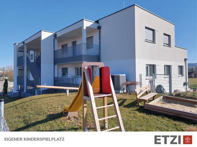 Modernes Wohngebäude mit eigenem Kinderspielplatz im Außenbereich.