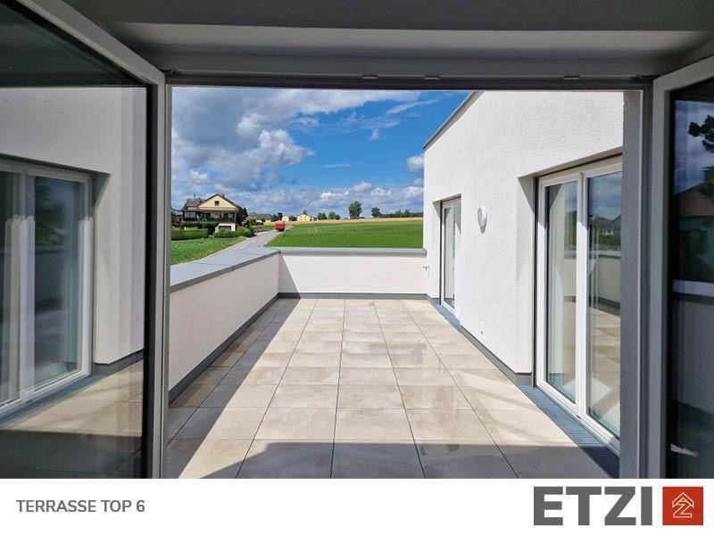 Geräumige Terrasse mit Fliesenboden und weitem Blick ins Grüne.