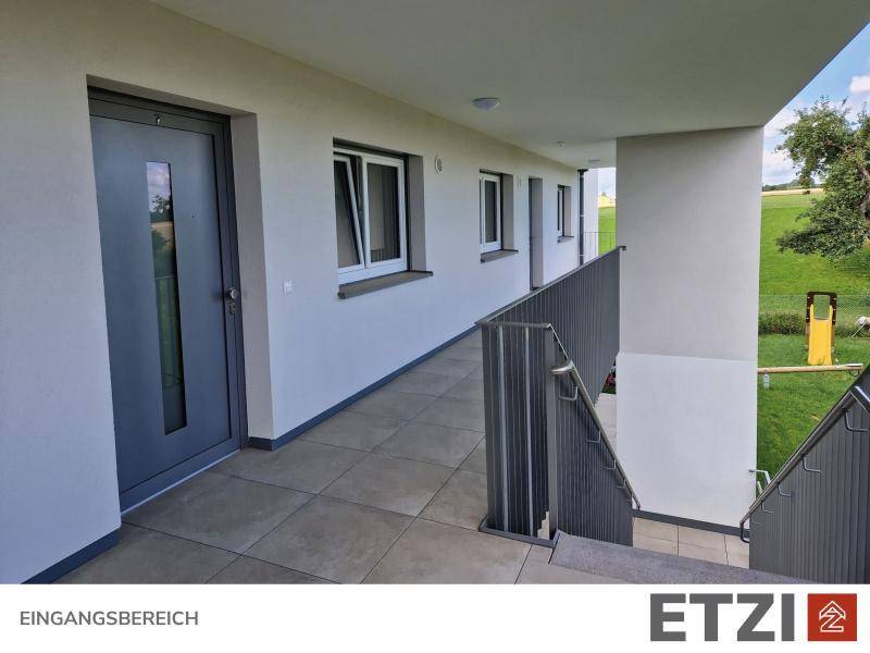 Überdachter Eingangsbereich mit Fliesenboden und Treppenaufgang.