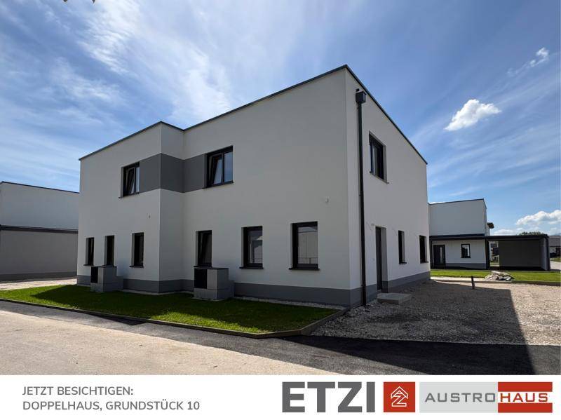 Neubau-Doppelhaus mit schlichter Architektur, weißer Fassade und Kiesbereich im Außenbereich.