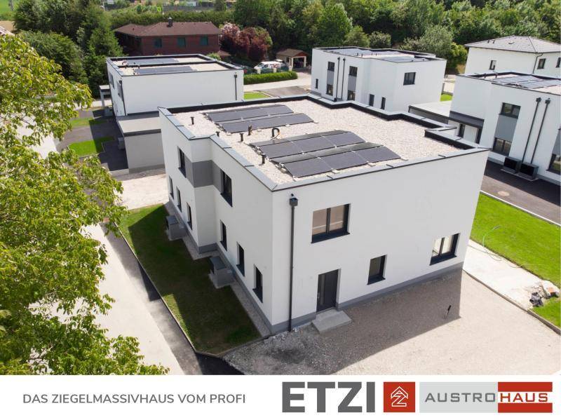 Modernes Einfamilienhaus mit Flachdach, Photovoltaikanlage und Eingangsbereich.