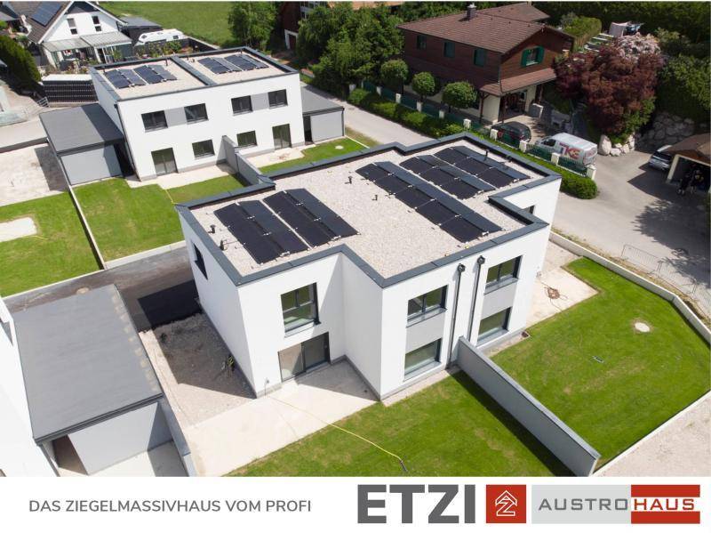 Einzelnes modernes Haus mit Photovoltaikanlage auf dem Flachdach und gepflegtem Garten.