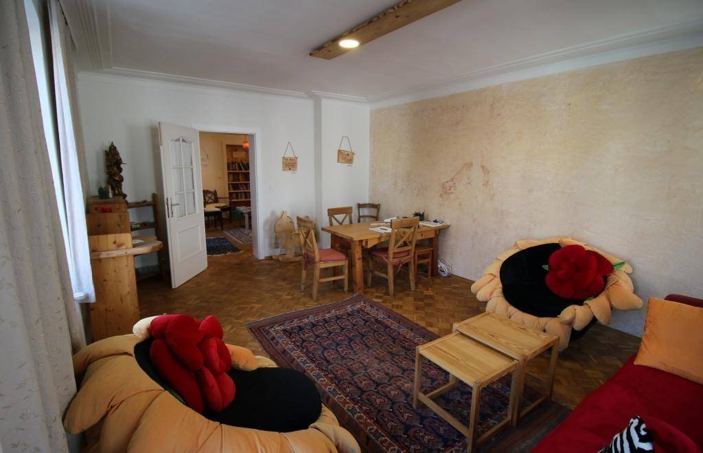 Heller Wohnraum mit bequemen Sitzgelegenheiten, Holztisch und Zugang zu einem weiteren Zimmer.