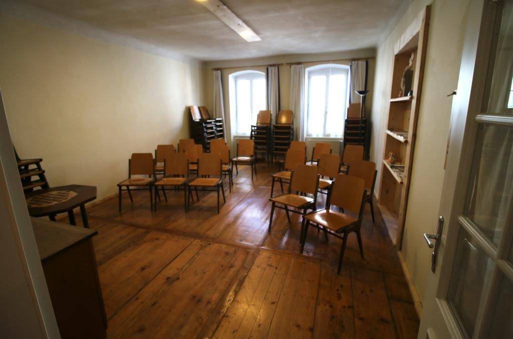Großer Konferenzraum mit Holzdielenboden und vielen Stühlen, bereit für Veranstaltungen oder Schulungen.