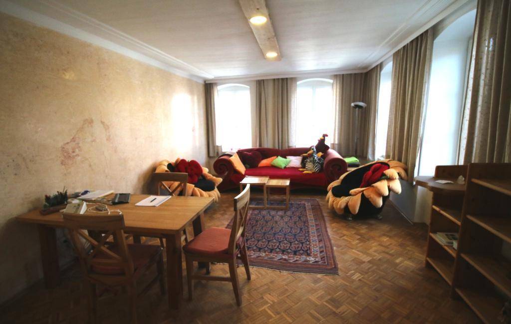 Gemütlicher Wohnbereich mit rotem Sofa, Holztisch und Teppich, ideal für Entspannung oder Besprechungen.