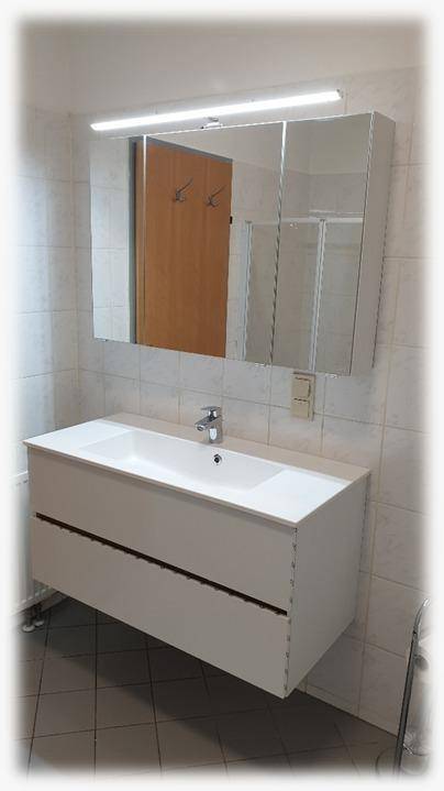 Helles Badezimmer mit modernem Waschtisch, Spiegelschrank und hellen Fliesen für eine zeitgemäße Optik.