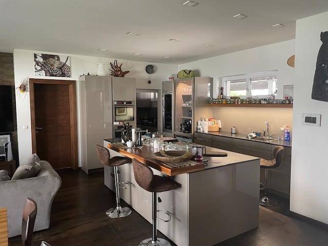 Moderne offene Küche mit großer Kücheninsel, Barhockern und integrierten Geräten in einem Wohnbereich.