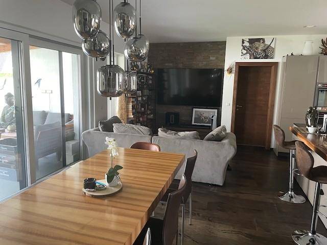 Heller Wohn-Essbereich mit großem Holztisch, modernen Pendelleuchten und Zugang zur Terrasse.