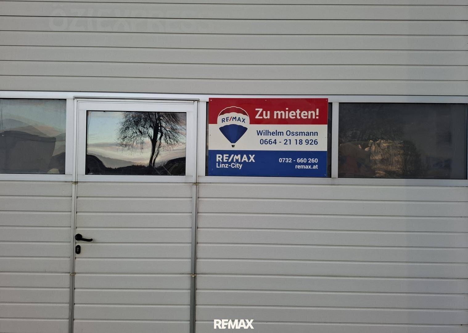 Nahaufnahme eines Garagentors mit einem "Zu vermieten"-Schild und einem kleinen Fenster.