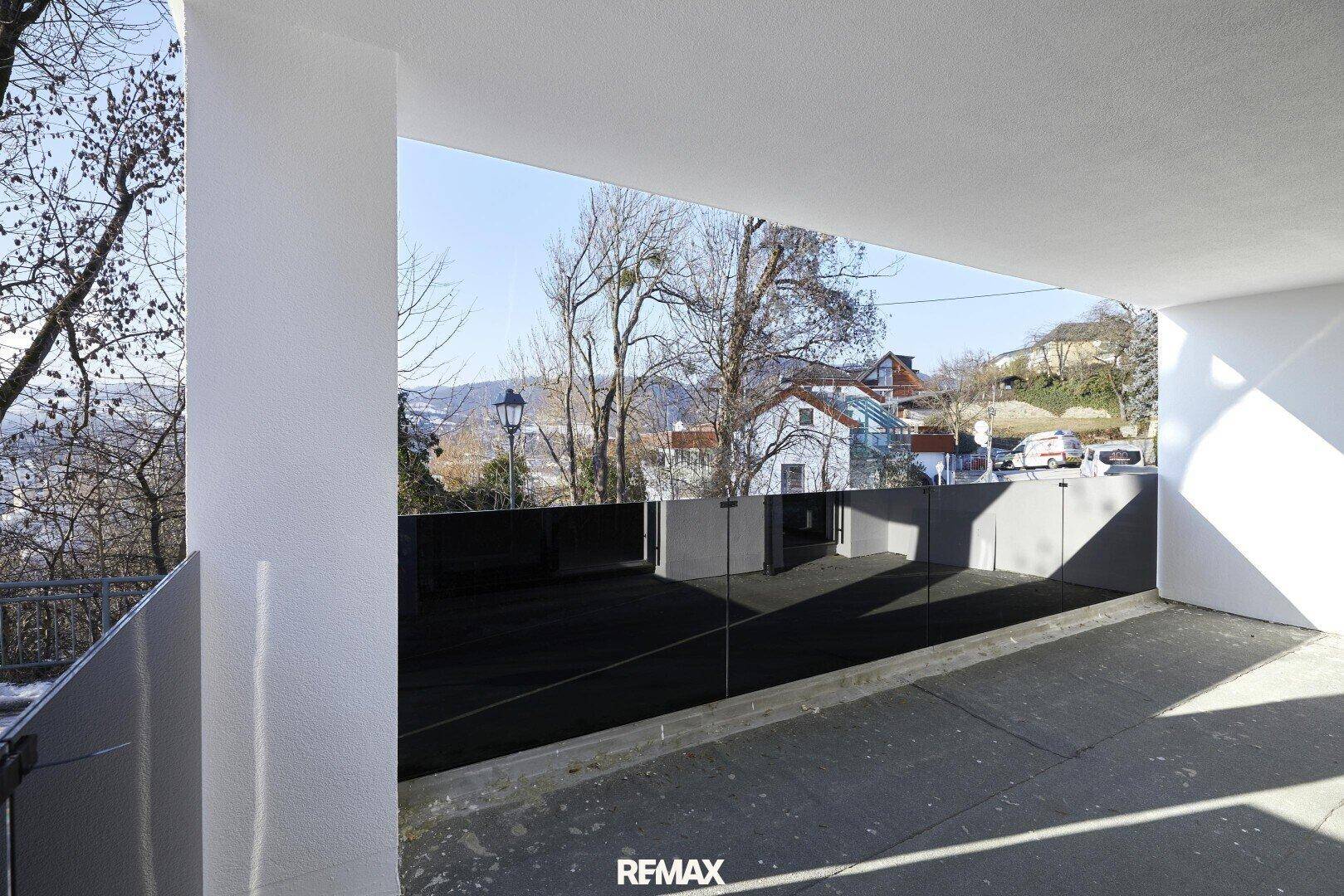 Moderner Balkon mit Glasbrüstung und weitem Blick auf die umliegende Landschaft.