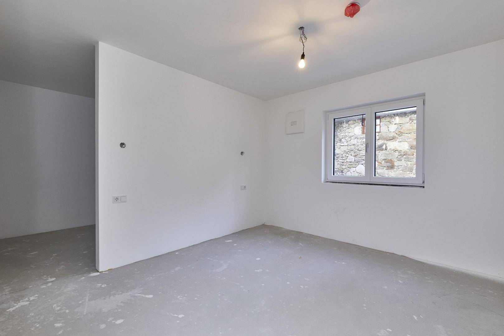 Unmöbliertes Zimmer mit Fenster und Blick auf die Umgebung, bereit für die individuelle Gestaltung.
