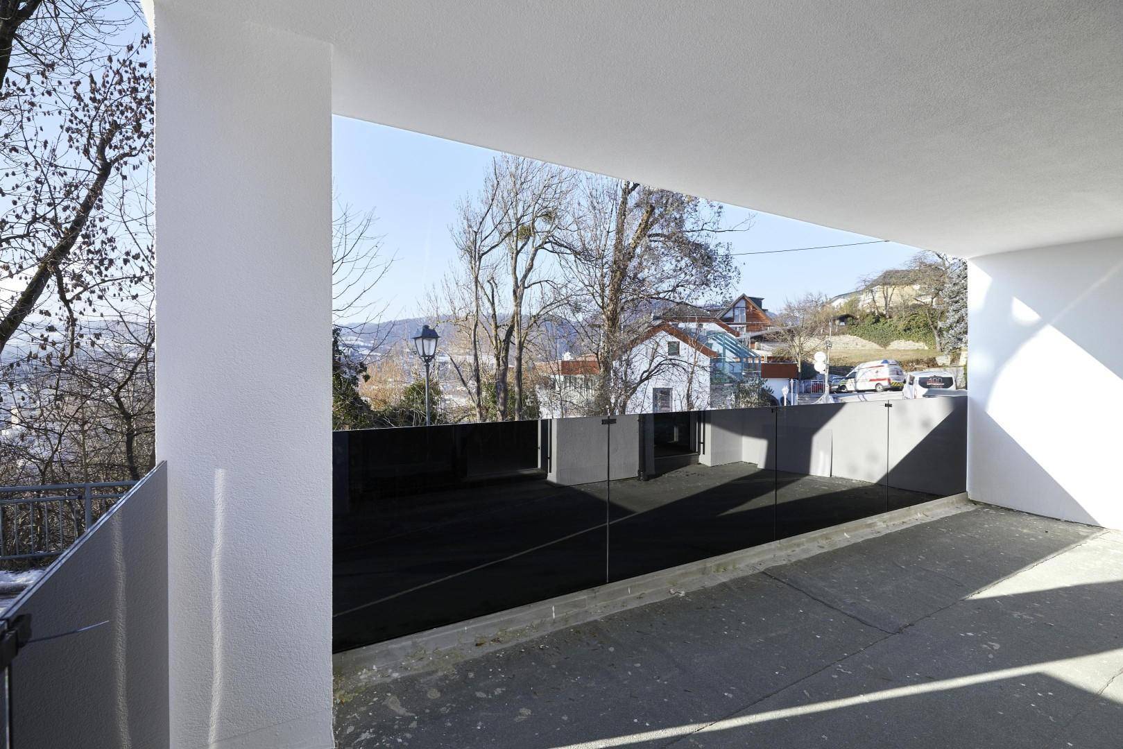 Moderne Terrasse mit Glasbrüstung und weitem Blick über die hügelige Landschaft.
