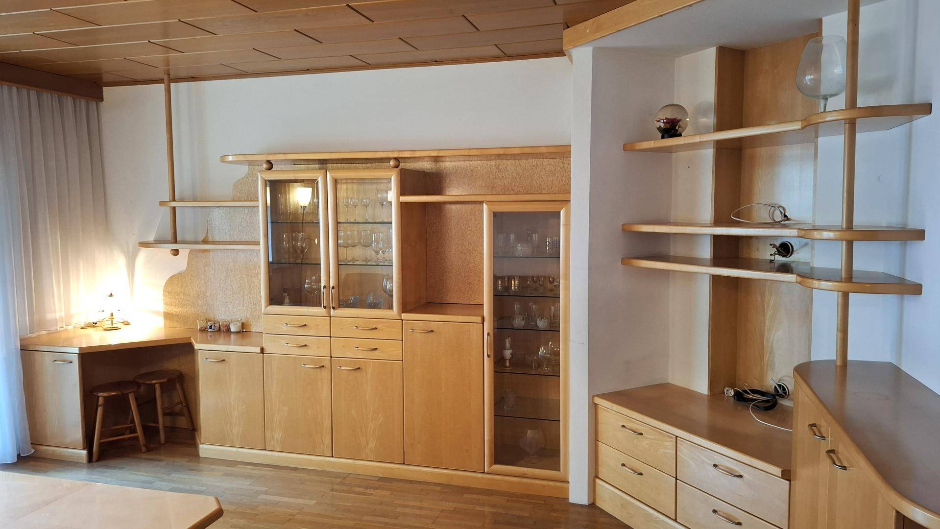 Detailansicht des Wohnzimmers mit integriertem Schreibtischbereich und Vitrinenschränken aus Holz.