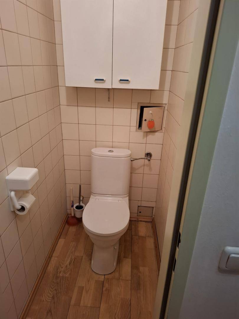 Separate Toilette mit WC, gefliesten Wänden und einem kleinen Hängeschrank.