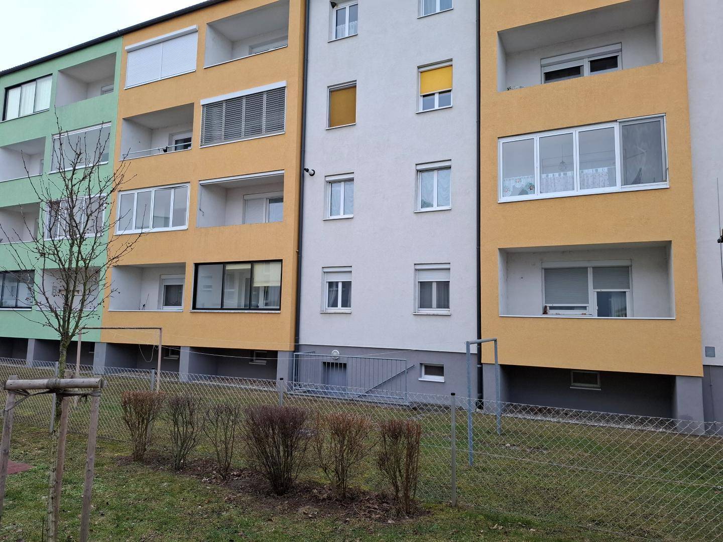Mehrfamilienhaus mit farbiger Fassade, Balkonen und Fenstern.