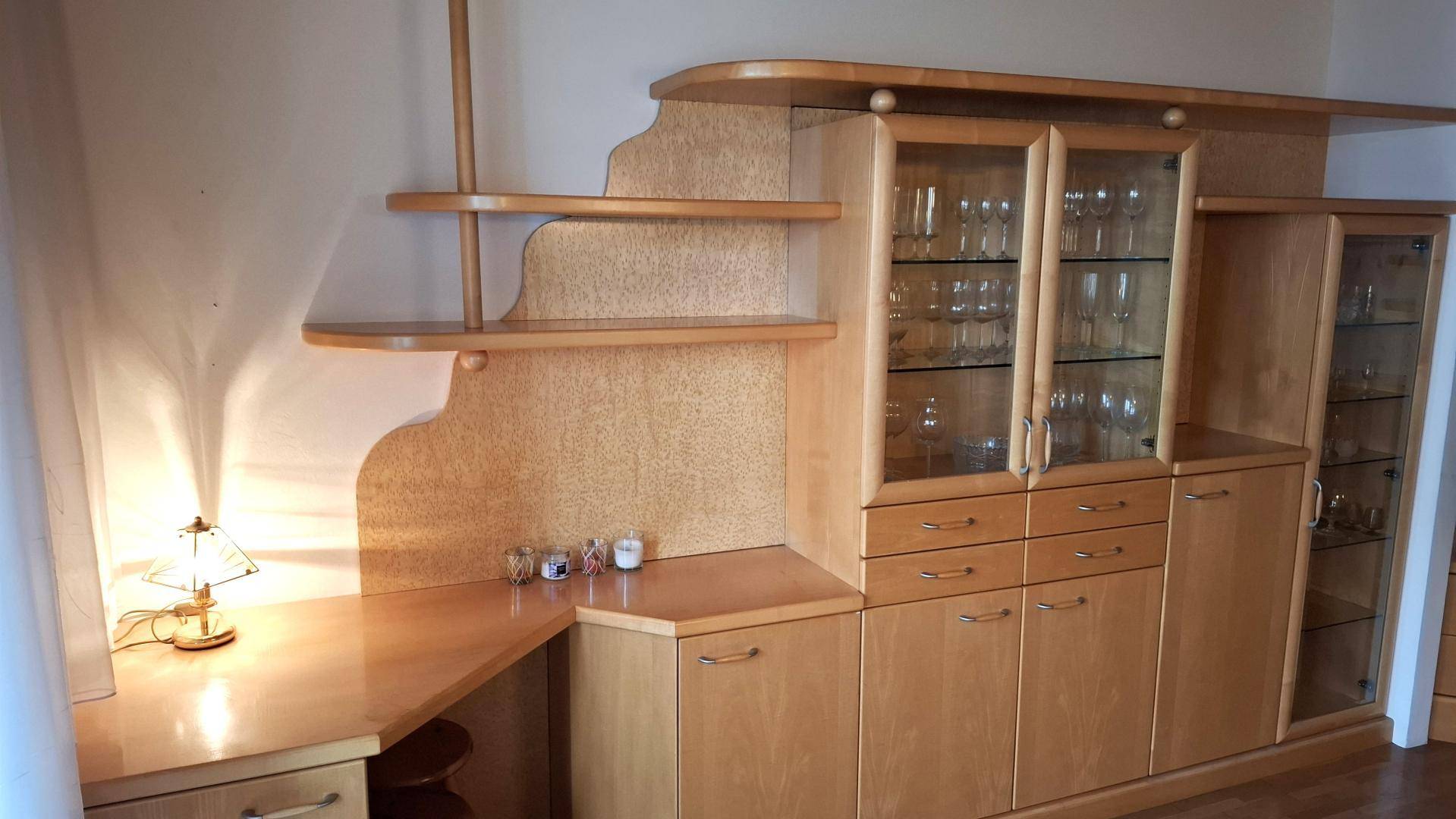 Detailansicht des Wohnzimmers mit integriertem Schreibtischbereich und Vitrinenschränken aus Holz.