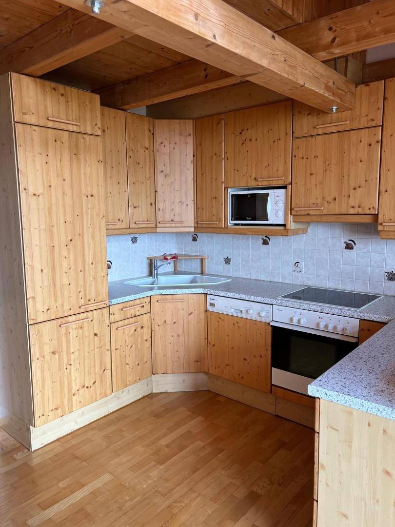 Rustikale Küche mit Holzschränken, integrierten Geräten und Holzbalkendecke.