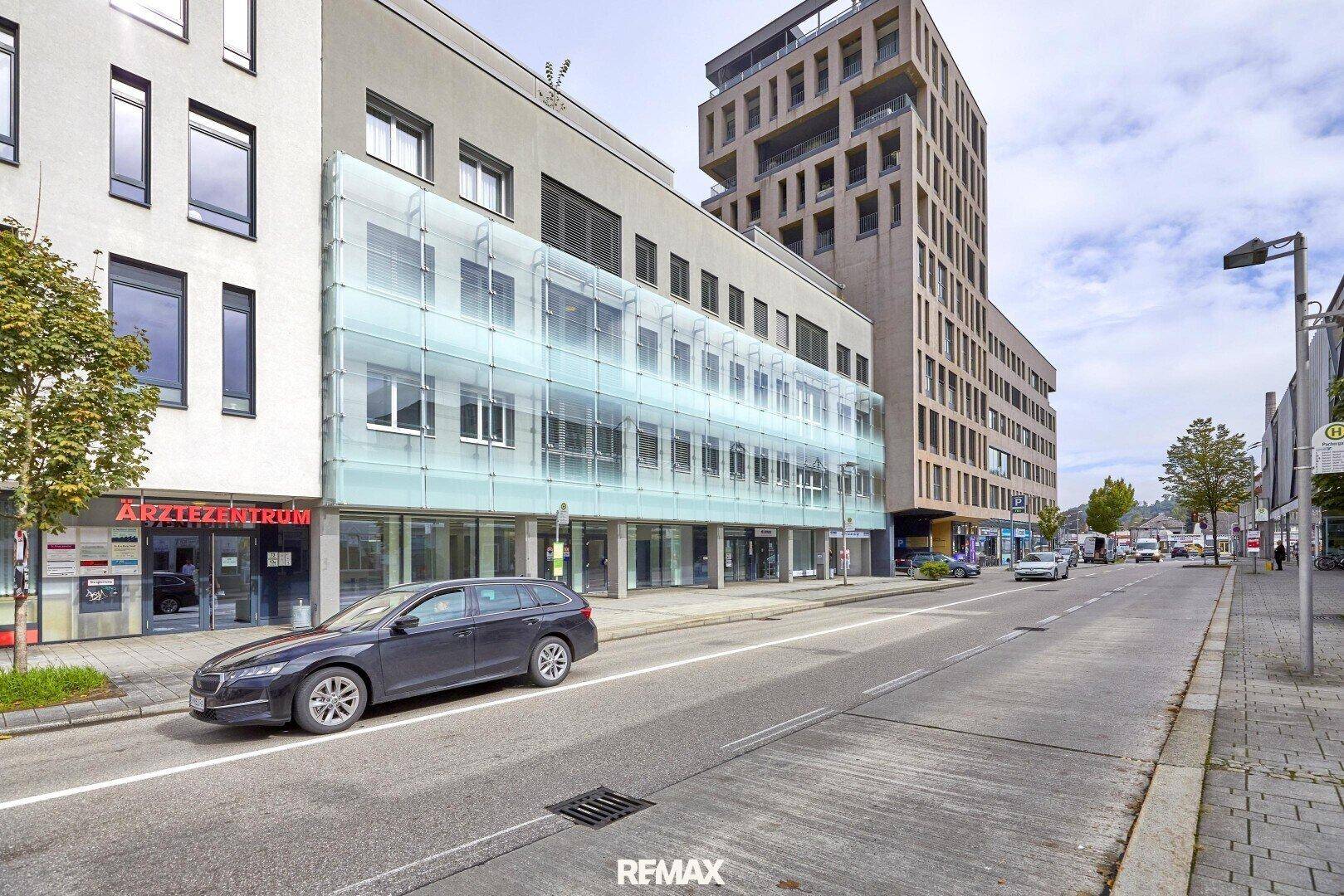 Weitläufige Straßenansicht mit dem modernen Geschäftsgebäude, umliegender Bebauung und städtischer Infrastruktur.