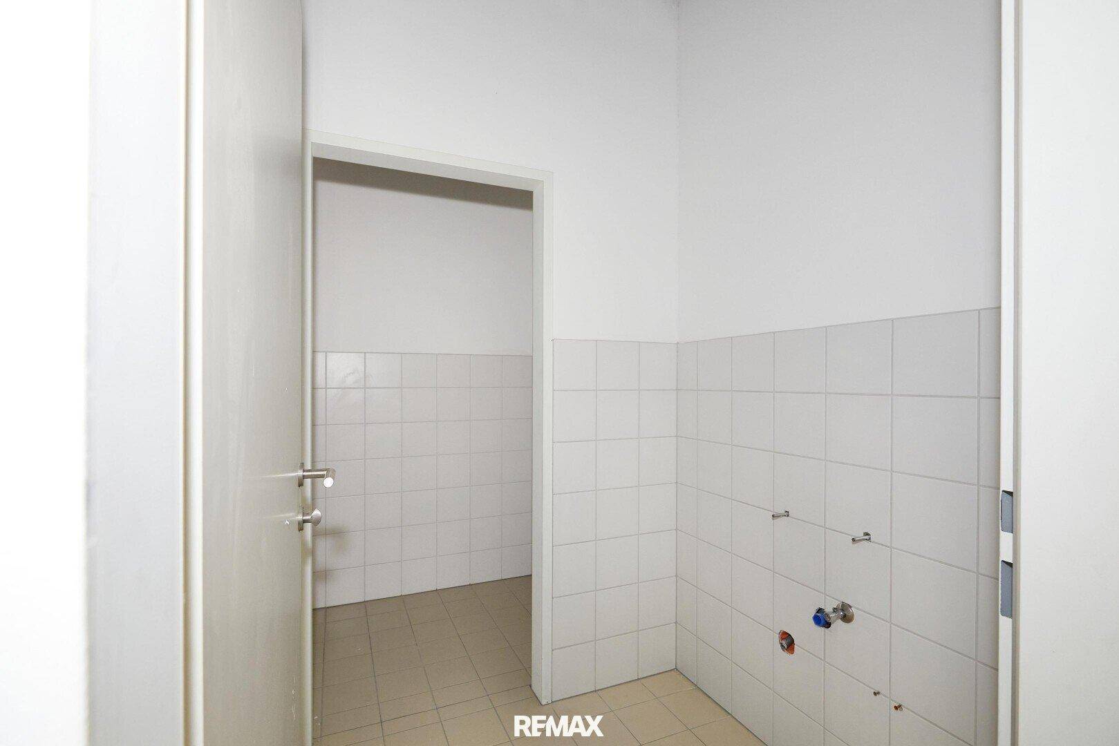 Nutzraum oder potenzieller Sanitärbereich mit weißen Fliesen an den Wänden und beigefarbenen Bodenfliesen, mit Anschlüssen.