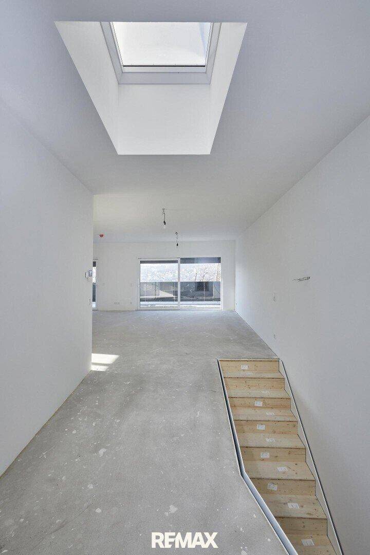 Heller Flur mit Treppe, Oberlicht und Blick auf den Außenbereich.