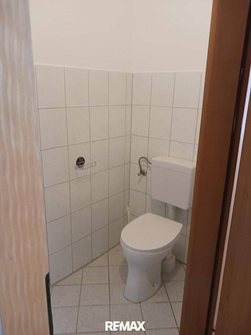 Kleines Gäste-WC mit weißen Fliesen und einfacher Toilettenausstattung.