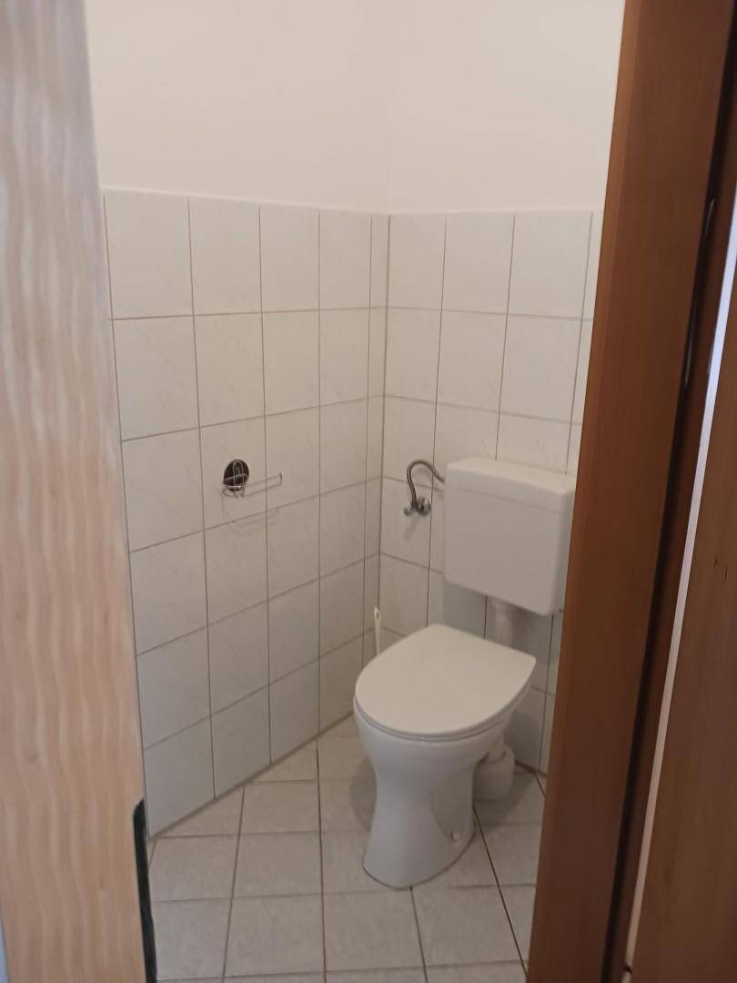 Kleines Gäste-WC mit weißen Fliesen und einfacher Toilette, funktional und sauber.