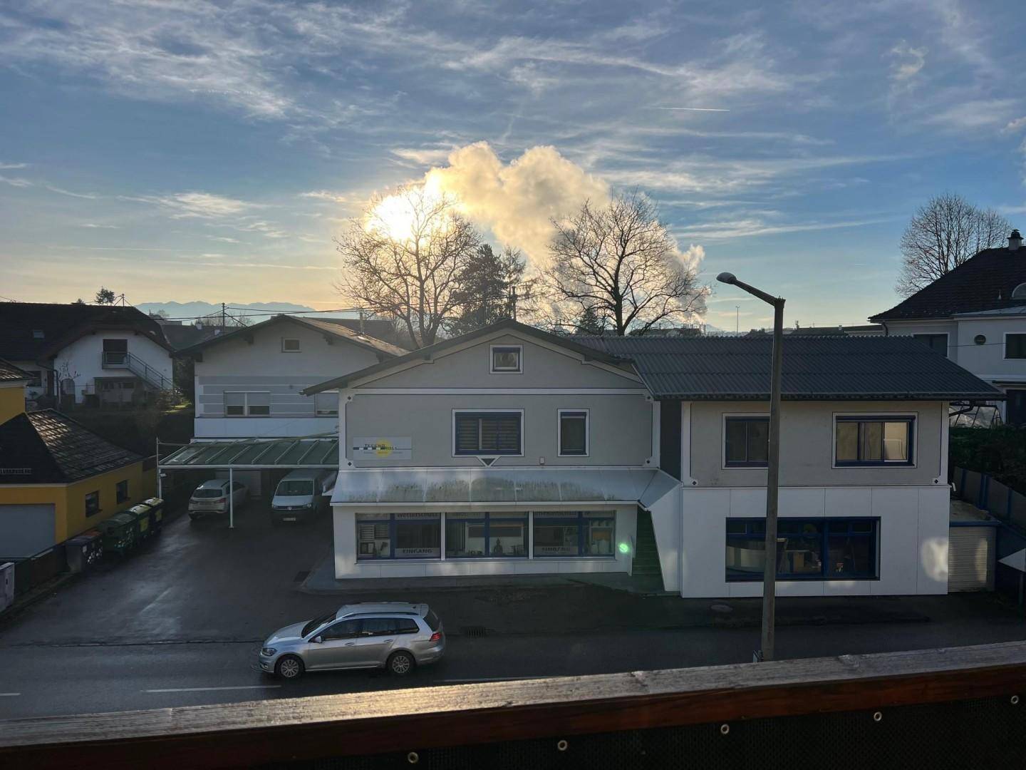 Gebäudeansicht mit gemischter Nutzung unter bewölktem Himmel und umliegender Bebauung.