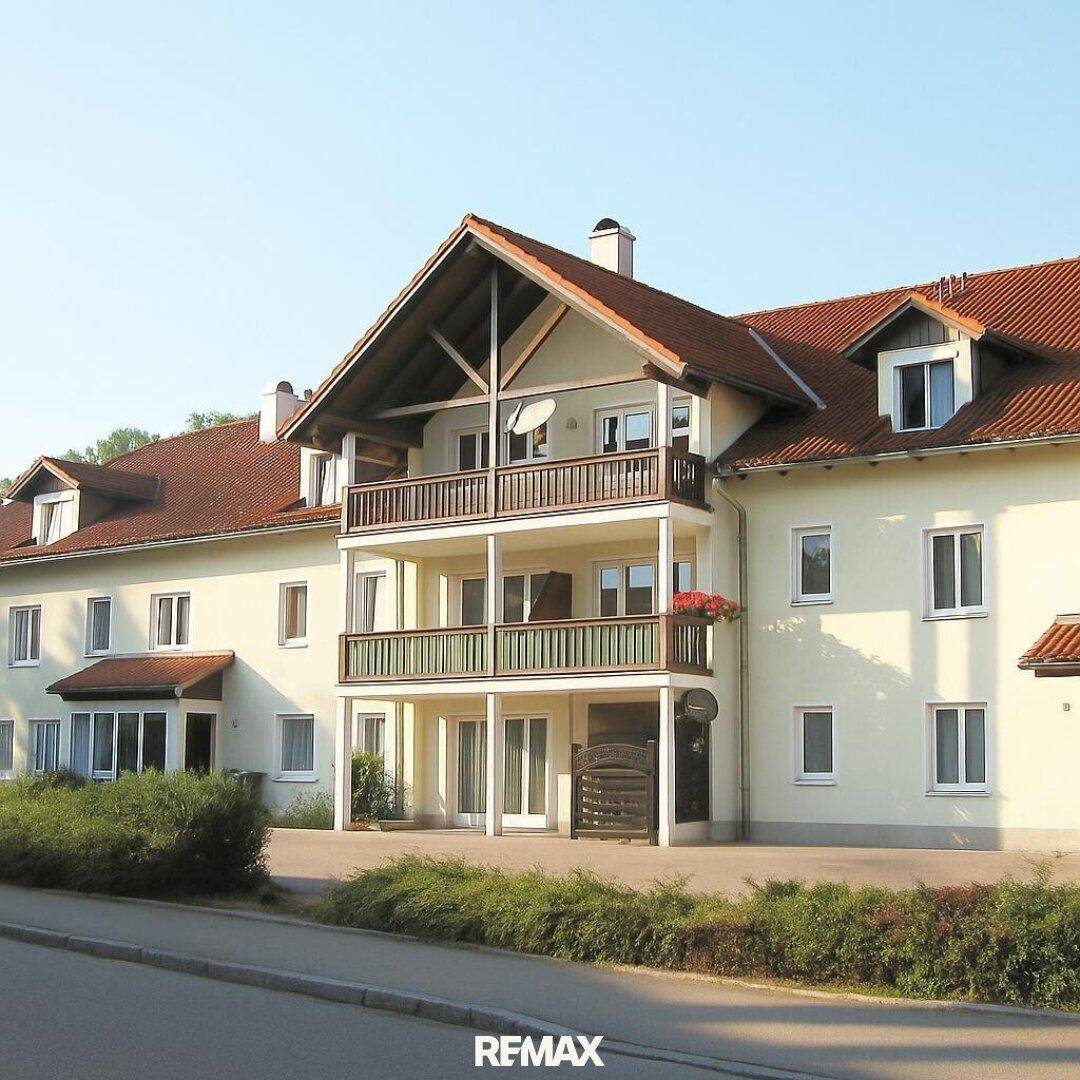 Mehrfamilienhaus mit mehreren Balkonen und traditionellem Ziegeldach in sonniger Lage.
