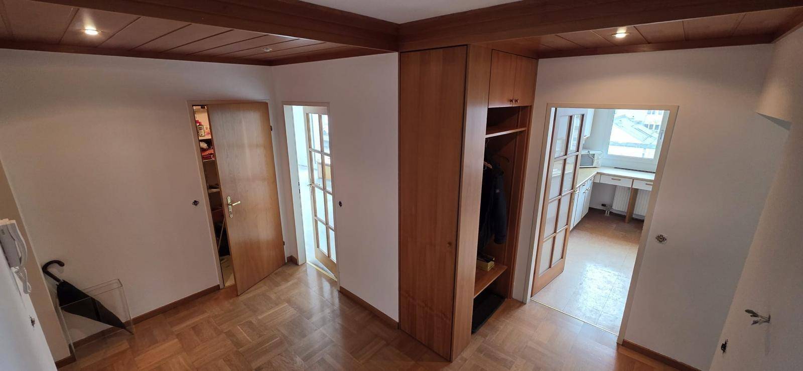 Flur mit Parkettboden, Holzdecke und integriertem Holzschrank, der zu weiteren Räumen führt.