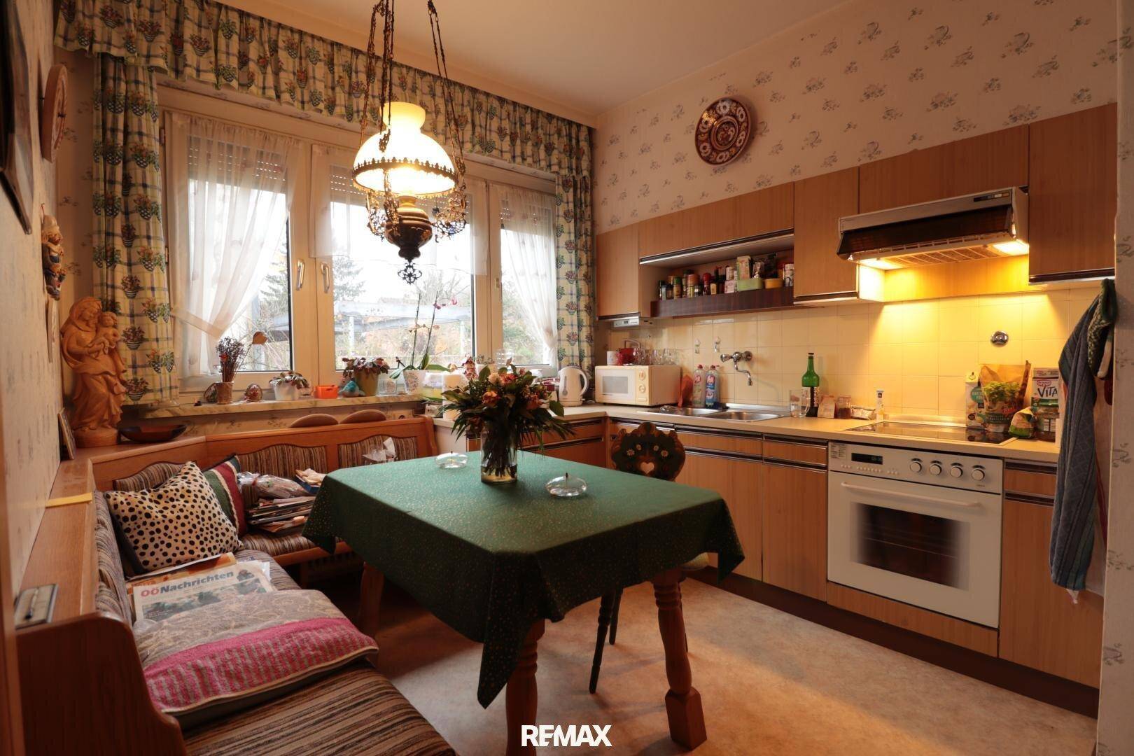 Gemütliche Wohnküche mit traditionellen Holzmöbeln, Essbereich und Fensterblick ins Grüne.