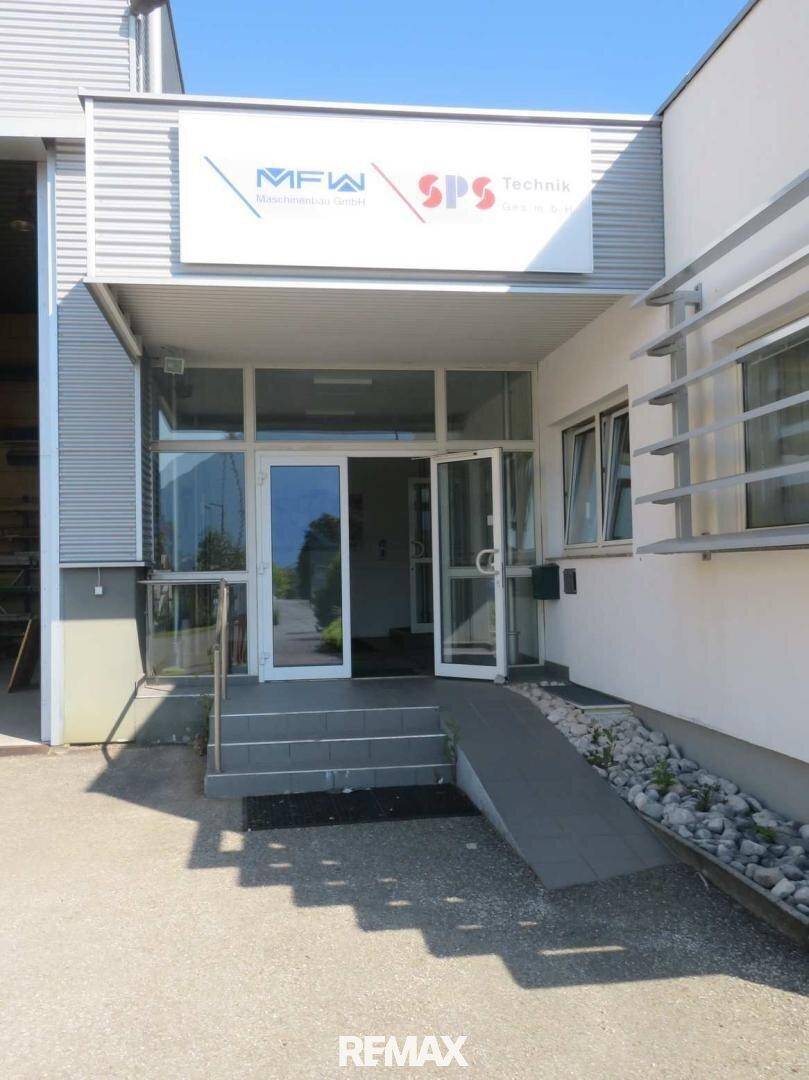 Eingangsbereich eines Bürogebäudes mit Treppe und einer Rollstuhlrampe für Barrierefreiheit.