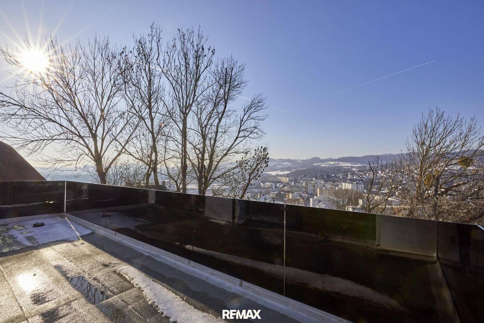 Weitläufiger Blick über die Stadt und die umliegende Landschaft von einer Dachterrasse im Winter.