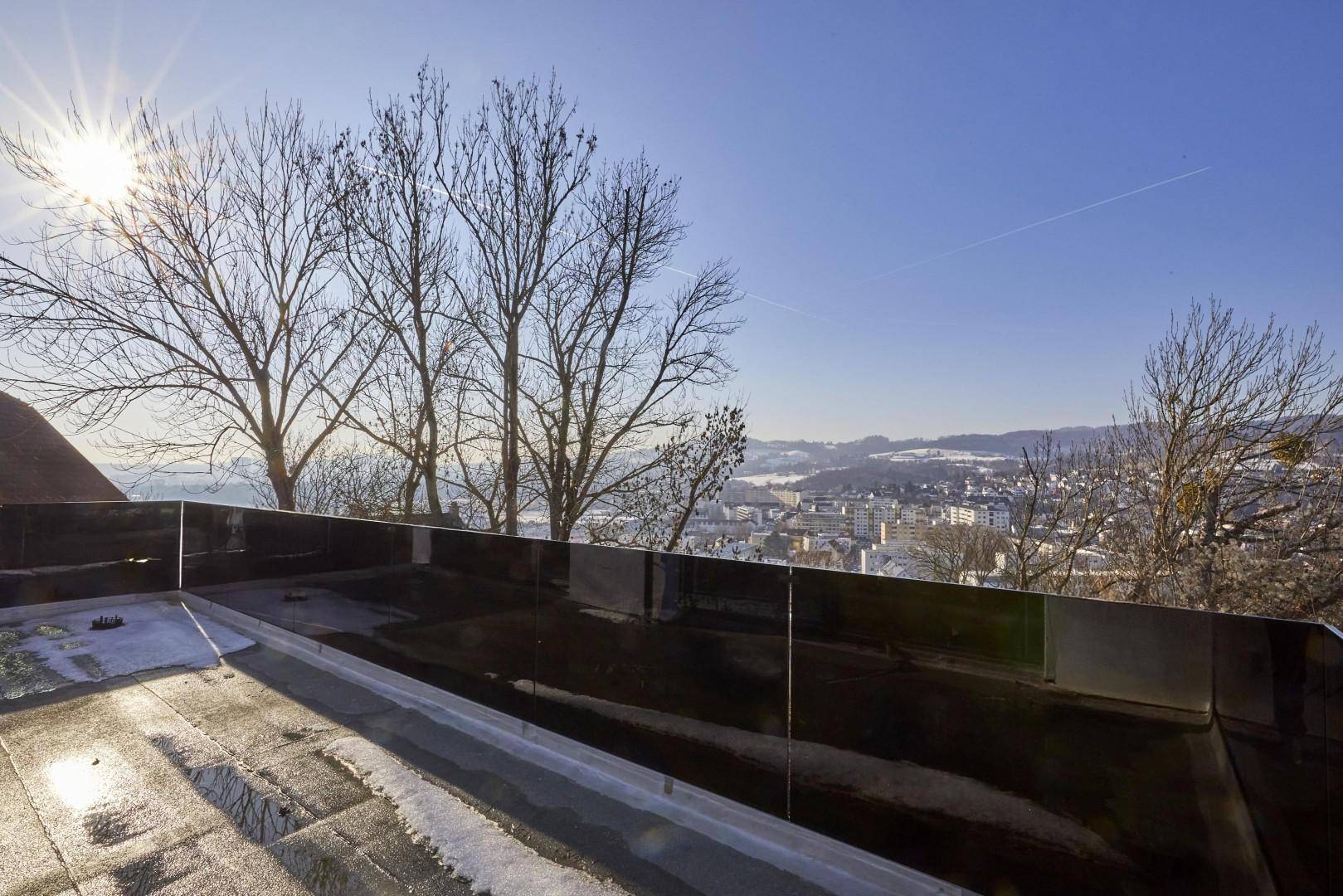 Weitblick über die Stadt und die verschneite Landschaft von einer Dachterrasse.