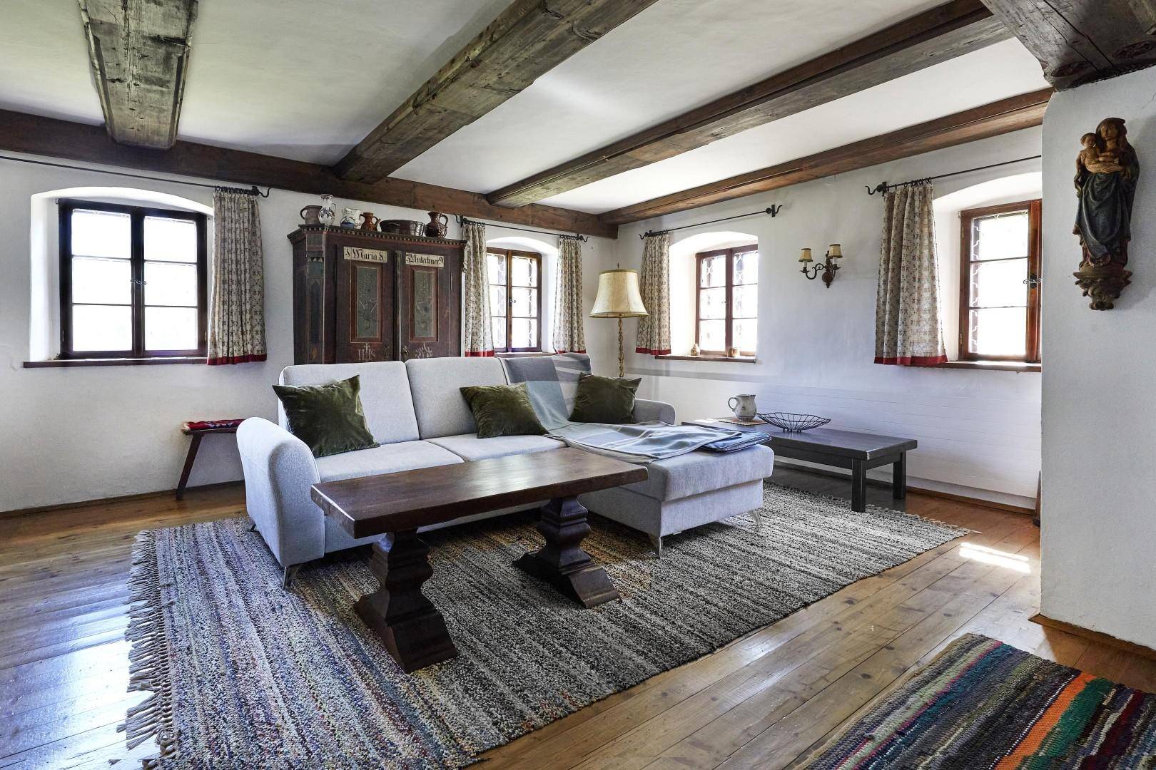 Helles Wohnzimmer mit bequemer Couch, Holzbalkendecke und traditionellen Möbeln.