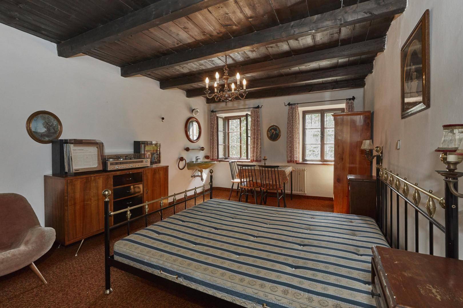 Schlafzimmer mit Holzbalkendecke, Metallbett und traditionellen Möbeln in gemütlicher Atmosphäre.