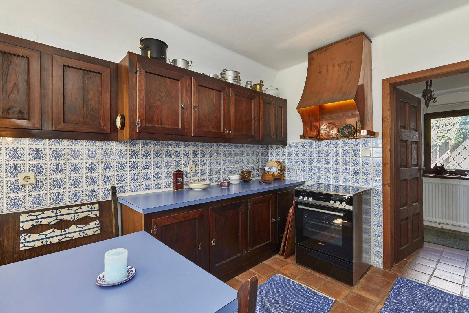 Traditionelle Küche mit dunklen Holzschränken, blauen Arbeitsplatten und gemusterten Fliesen.