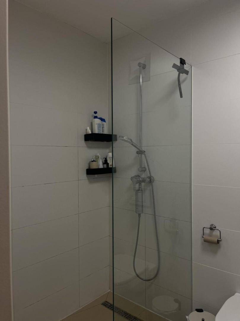 Modernes Badezimmer mit begehbarer Dusche und großen weißen Fliesen an den Wänden.